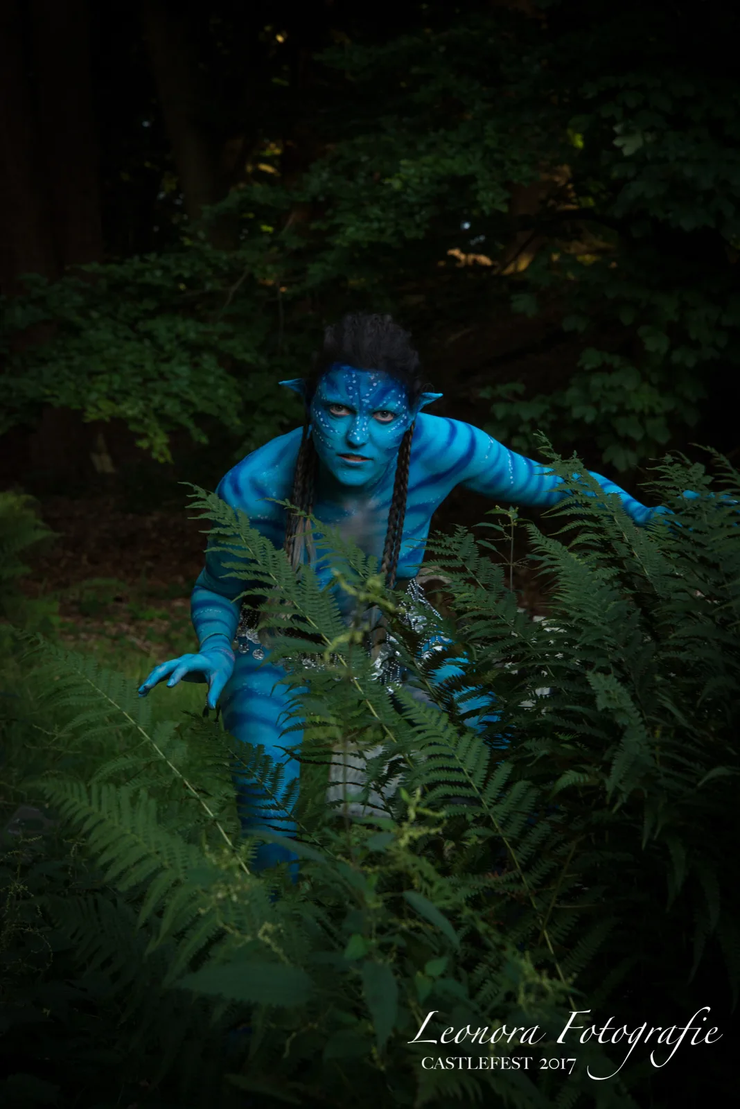 Blauwe fantasywezen bodypaint tussen varens
