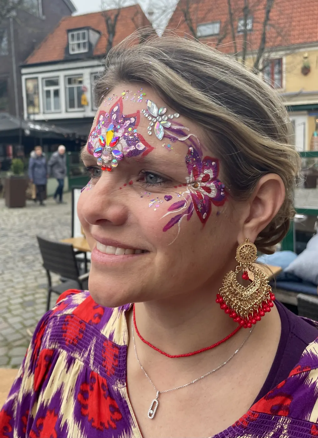 Lachende bezoekster met bloemschmink en glitters op een evenement